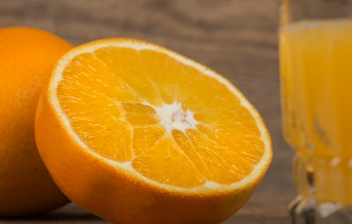La naranja, mucho más que vitamina C: naranja partida por la mitad y un vaso de zumo al lado