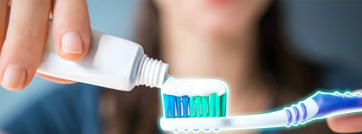 Mujer echando pasta de dientes sobre un cepillo