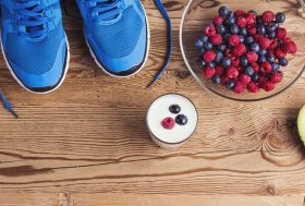 Alimentación para recuperarse tras una maratón: zapatillas de deporte, bol de frutas sobre tabla de madera