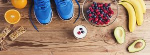 Alimentación para recuperarse tras una maratón: zapatillas de deporte, bol de frutas sobre tabla de madera