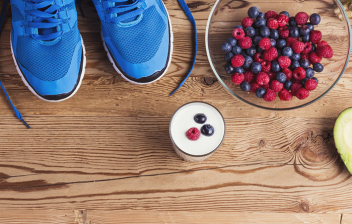 Alimentación para recuperarse tras una maratón: zapatillas de deporte, bol de frutas sobre tabla de madera
