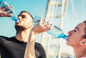 Bebidas deportivas: chico y chica bebiendo agua después de hacer ejercicioi