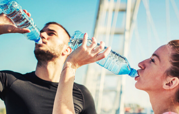 Bebidas deportivas: chico y chica bebiendo agua después de hacer ejercicioi