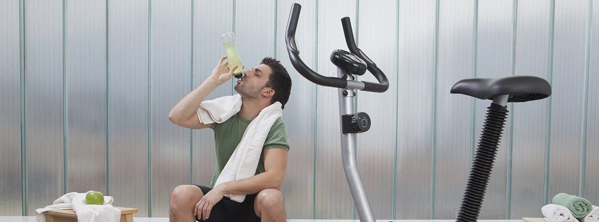 Bebidas poara deportistas: hombre en el gimnasio bebiendo una bebida isotónica
