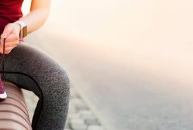 Nutrientes esenciales para el corredor: deportista atándose la zapatilla de correr y un batido de nutrientes al lado
