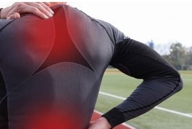 ¿Cómo prevenir el dolor de espalda al corredor?: deportista en pista de atletismo con problemas en la espalda