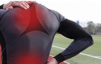 ¿Cómo prevenir el dolor de espalda al corredor?: deportista en pista de atletismo con problemas en la espalda