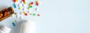 ¿Qué son y qué ventajas tienen los medicamentos combinados?: 3 frascos abiertos de medicamentos y pastillas alrededor