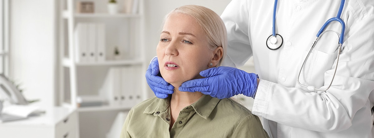 Médico explorando el cuello de una paciente