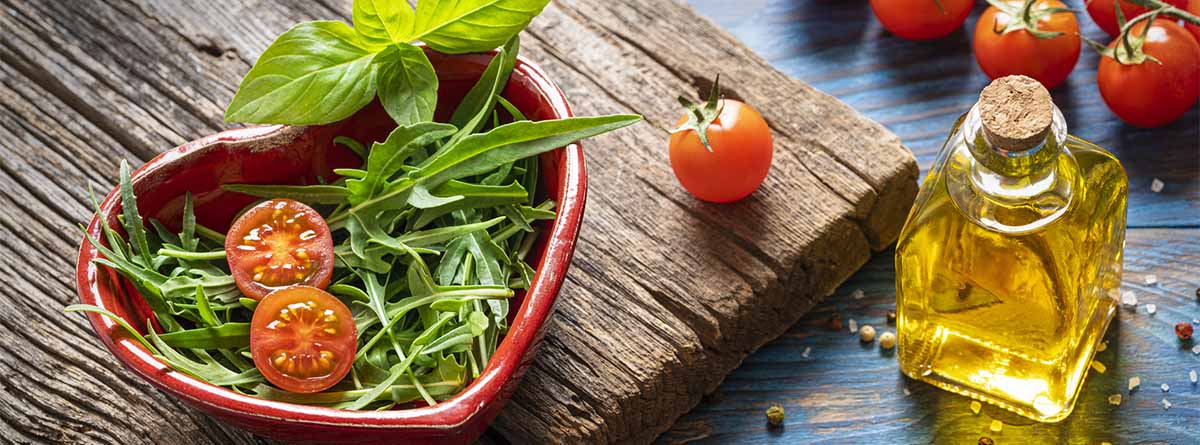 Alimentación cardiovascular: recipiente de barro en forma de corazón con verduras sobre tabla de madera