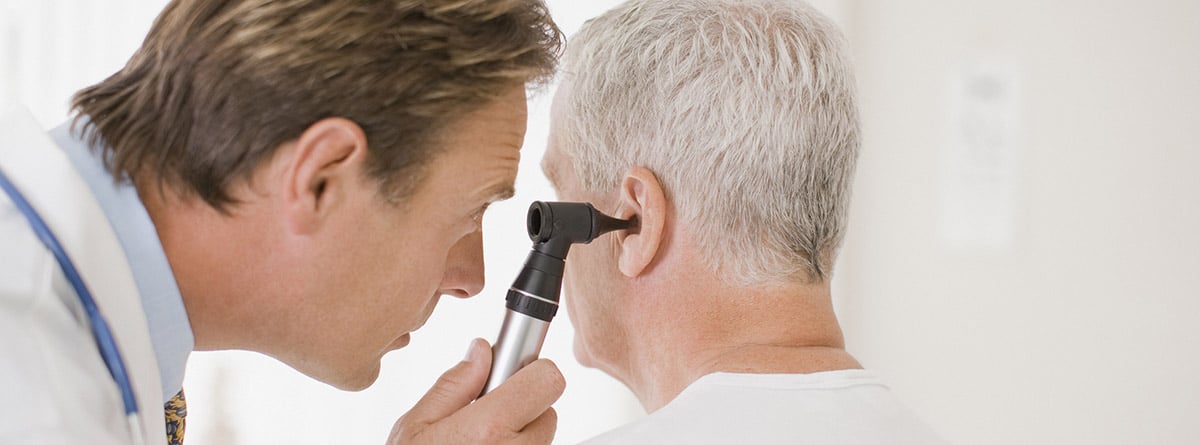 ¡Qué hace un otorrino y cuándo visitarlo?: otorrino inspecionando el oído de un paciente en la consulta