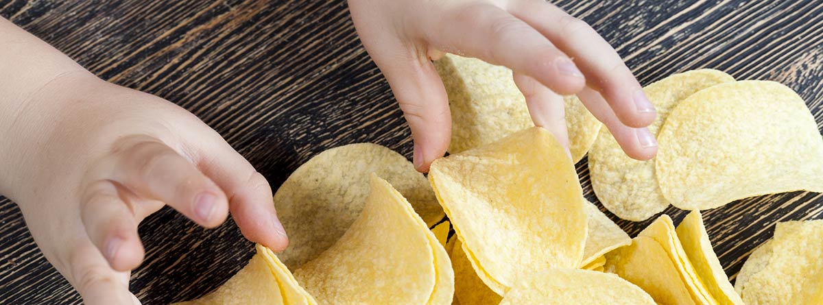 Cuanta sal pueden tomar los niños: manos de niño cogiendo patatas fritas