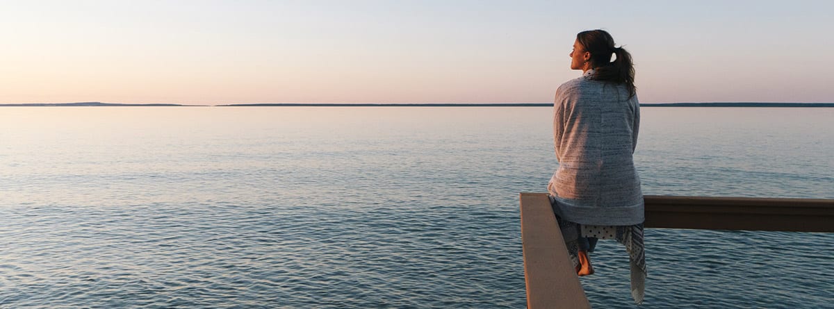 Chica sentada sobre una barandilla mirando al horizonte