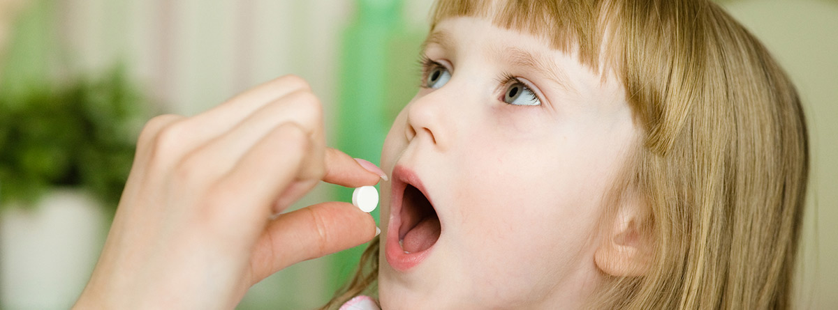 Uso correcto de medicamentos en niños: madre dando una pastilla a una niña