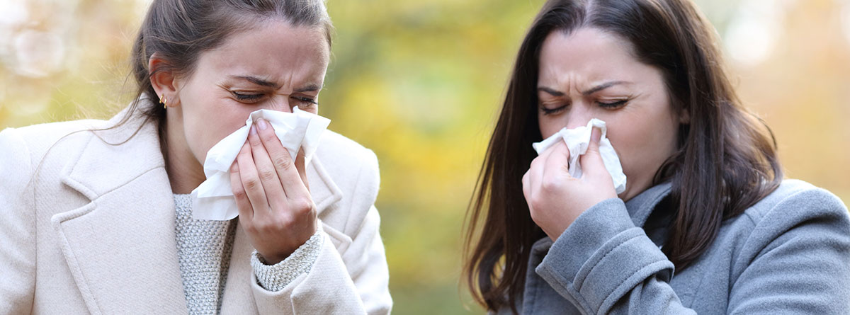Color del moco: dos mujeres sonándose la nariz con síntomas de gripe