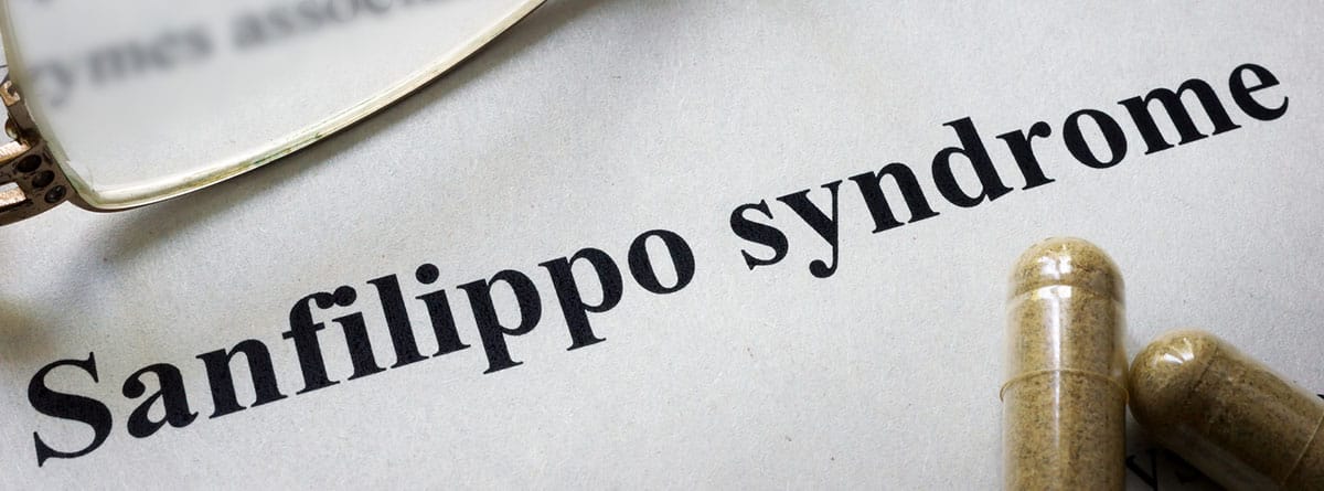 Hoja de papel con la palabra síndrome de san Filippo en inglés, unas gafas al lado y unas pastillas