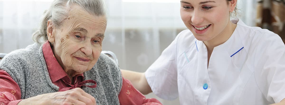Enfermera ayudando a una mujer mayor
