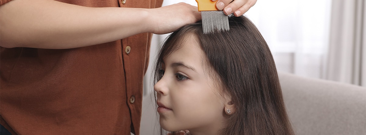 Mujer pasando una lendrera en el cabello de una niña