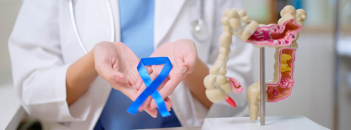 Cáncer de recto: doctora con un lazo azul en las manos con un módelo de recto