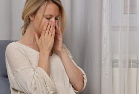 ¿Por qué tengo dolor en el tabique nasal?: mujer joven rubia con las manos en la nariz