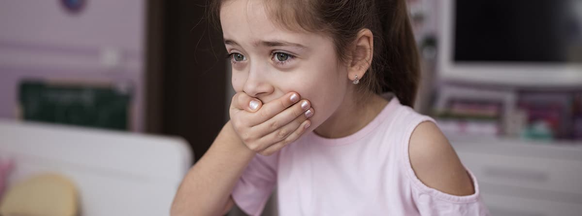 Intoxicación por hierro en niños: niña vestida de rosa con la mano en la boca .