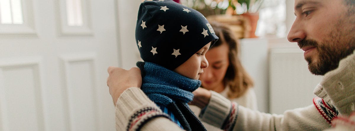 Foto de una familia joven poniéndose ropa abrigada y preparándose para las actividades invernales.