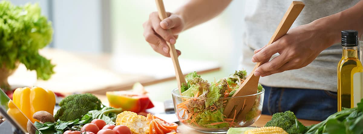 Recomendaciones de nutrición para el hombre: hombre dando vueltas a una ensalada, alrededor diferentes alimentos de dieta saludable