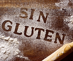 Prevenir la celiaquía, alimentos sin gluten: harina esparcida sobre tabla de madera y escrito las palabras sin gluten