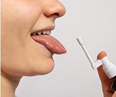 Candidiasis bucal: mujer con la lengua fuera aplicándose un medicamento
