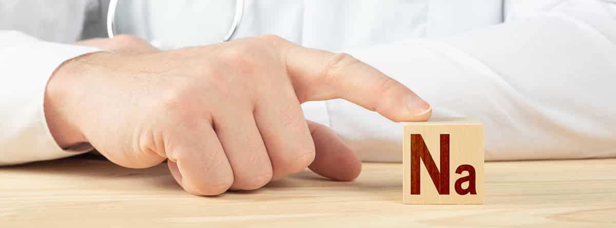 Causas del déficit de sodio: médico apoyando un dedo en un cubo de madrera con las letras Na