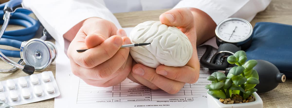 Gliomas: especialista con un cerebro de plástico en la mano explicando una patología
