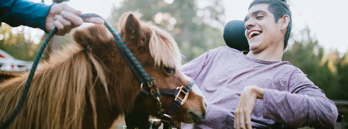 Equinoterapia, la terapia con caballos: joven con discapacidad con un pony