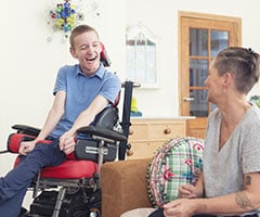 ¿Qué es el ELA?: Imagen en color de un joven paciente de ELA con discapacidad física de la vida real que pasa tiempo con su madre en casa