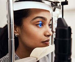 ¿Qué es la hipermetropía?:Foto de una mujer joven que se examina los ojos con una lámpara de hendidura