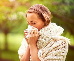 Rinitis alérgica: mujer joven que se suena la nariz