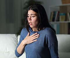 Shock anafiláctico: mujer con falta de respiración poniendo la mano en el pecho