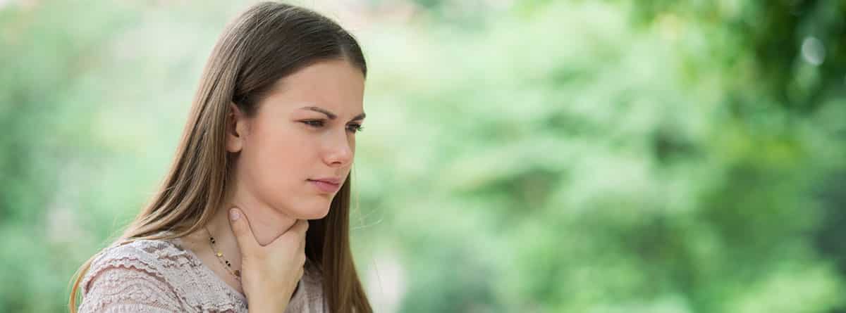 Causas del dolor de garganta: chica joven en el campo con dolor de garganta