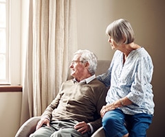 Tipos de demencia y el alzheimer: pareja mayor mirando cuidadosamente por una ventana en casa