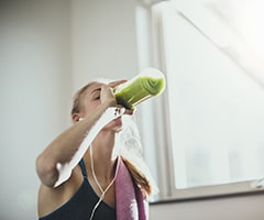 Como llevar la dieta DASH: Mujer joven recibiendo su batido verde después del entrenamiento