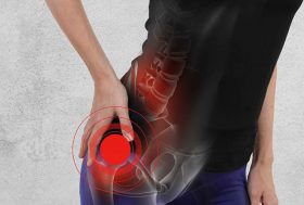 Causas del dolor de cadera: deportista con la mano sobre la cadera y un circulo rojo