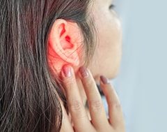 Dolor de oídos: perfíl de cara de mujer con la oreja enrojecida