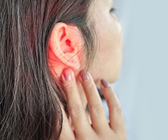 Dolor de oídos: perfíl de cara de mujer con la oreja enrojecida