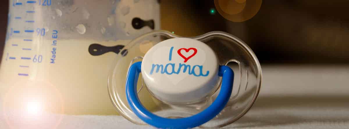 ¿Qué beneficios tiene la lactoferrina?: biberón con leche materna y un chupete con la palabra mamá