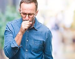 ¿Qué es la tos? hombre con camisa vaquera tosiendo