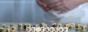 Incompatibilidad rh en el embarazo: Palabra factor RH compuesto por letras de madera. mujer embarazada en el fondo