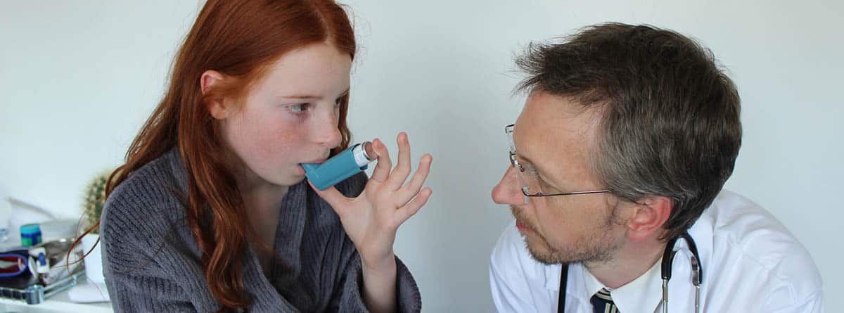 Broncoespasmos: médico enseñando a paciente joven usar un inhalador