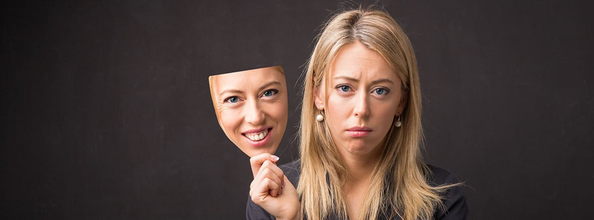 Qué es la depresión sonriente: mujer joven con el rostro serio y su propia máscara sonriendo