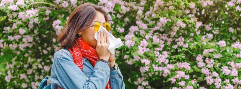 Mujer joven con un pañuelo en la nariz a consecuencia de la alergia