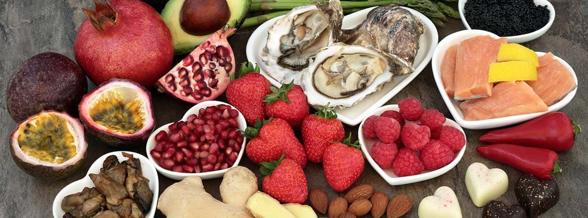 Cuáles son los alimentos afrodisíacos: fresas, ostras, chocolate, aguacate sobre bols con forma de corazón