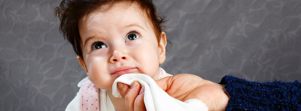 Tipos de vómitos en bebés: madre limpiando la barbilla a un bebé